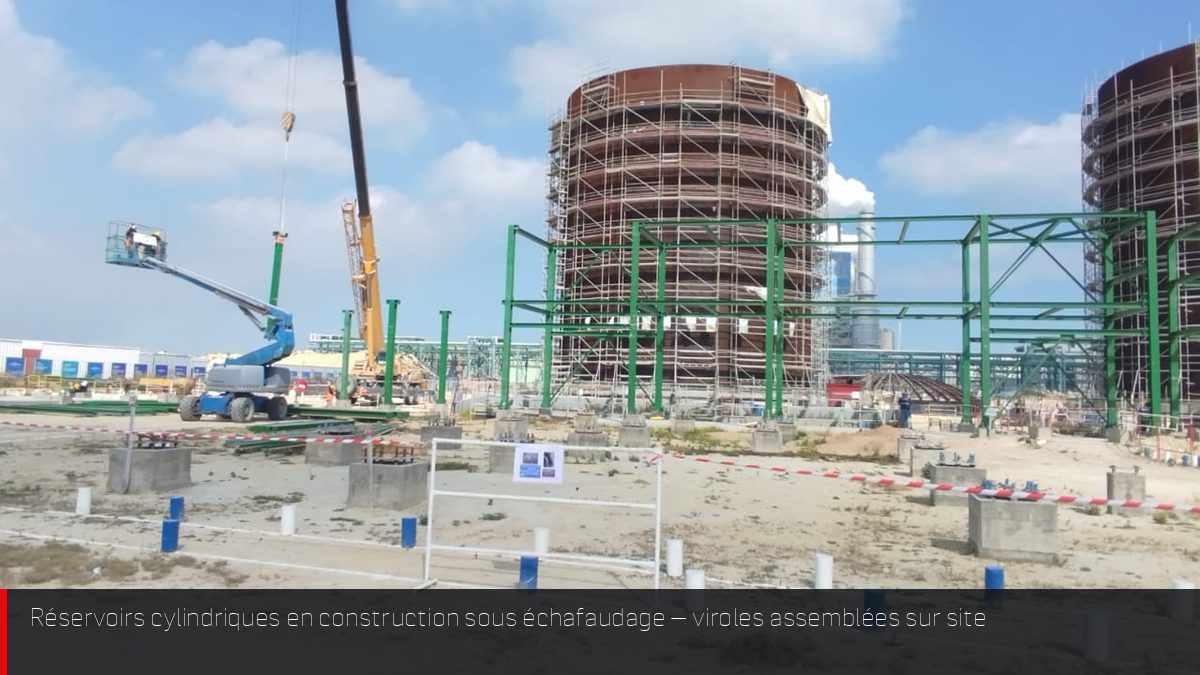Réservoirs industriels cylindriques en cours de montage avec échafaudages sur site