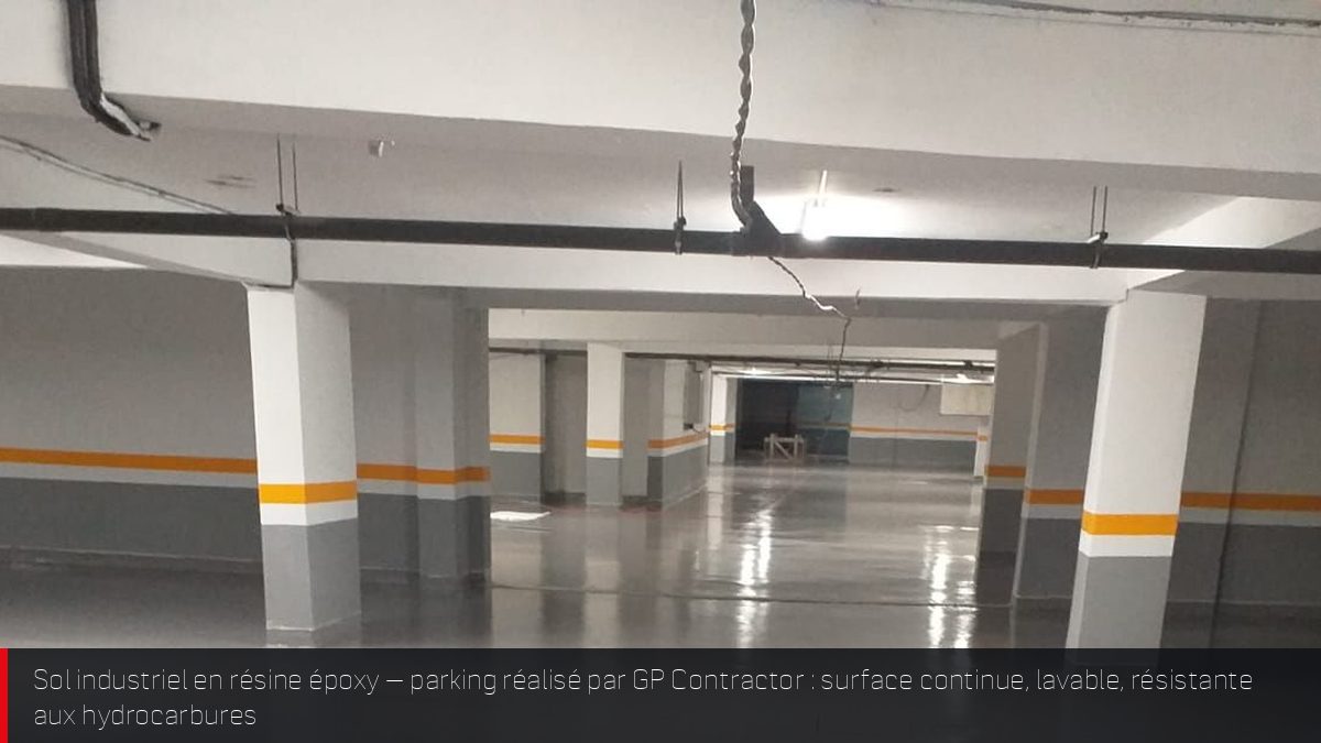 Sol en résine époxy gris clair dans un parking industriel avec poteaux à bandes jaunes